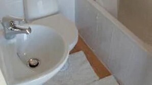 A bathroom with a white sink, a toilet, and a shower area. - Bennys B and B (London)