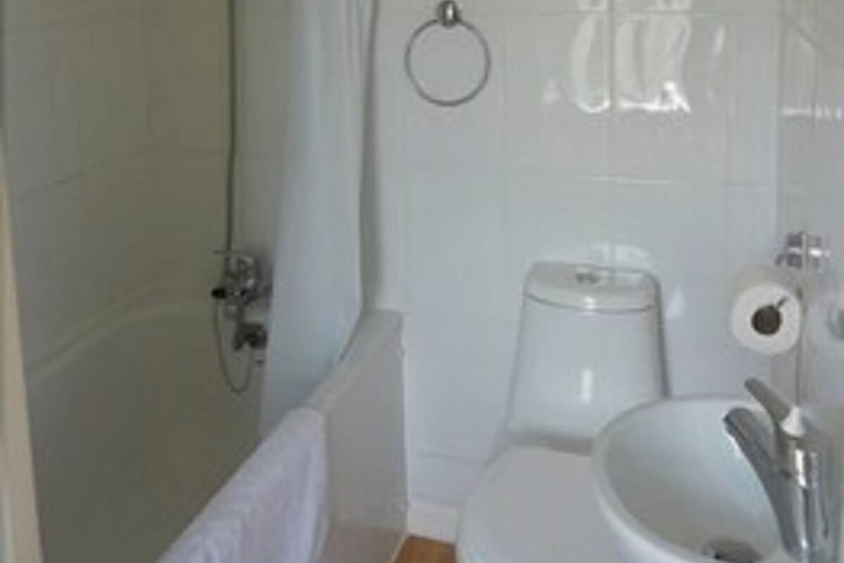A bathroom with a shower, toilet, sink, and a towel rack.