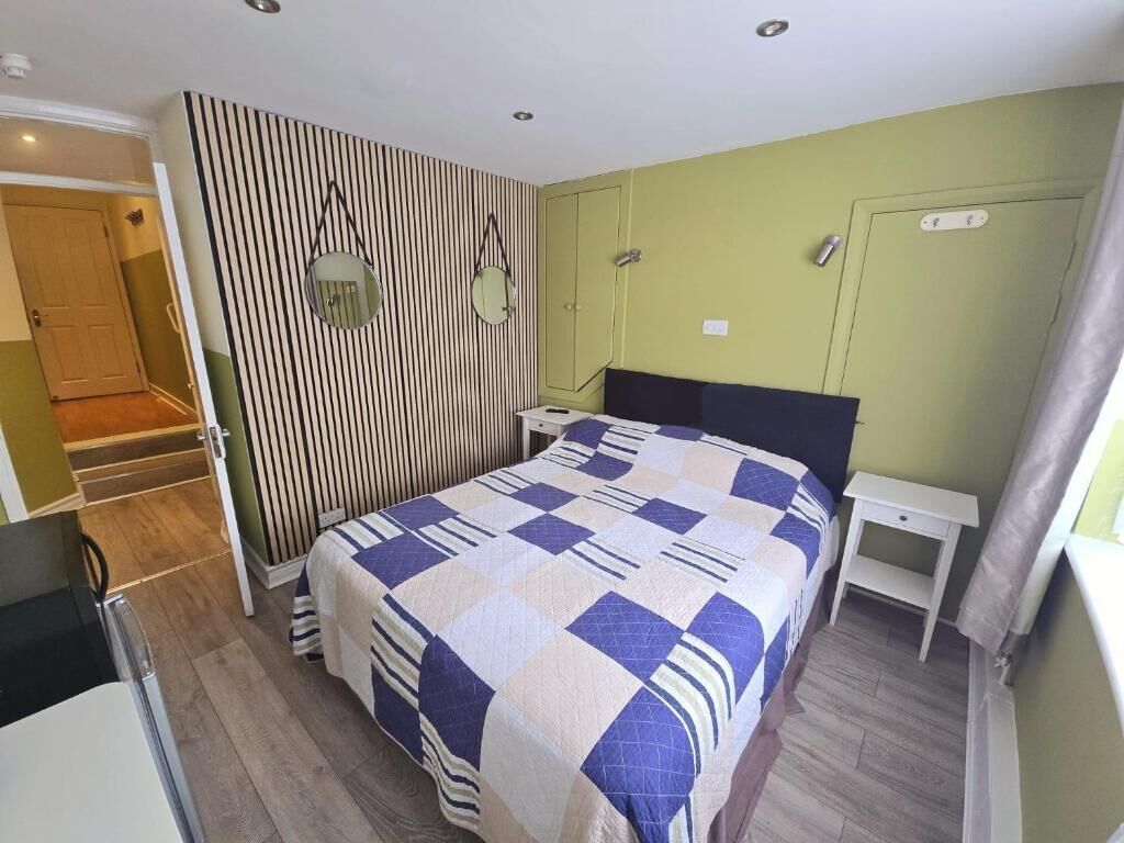 Un dormitorio con cama, mesitas de noche, un armario y un espejo.