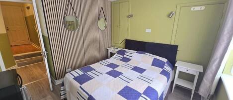 Un dormitorio con cama, mesitas de noche, un armario y un espejo.