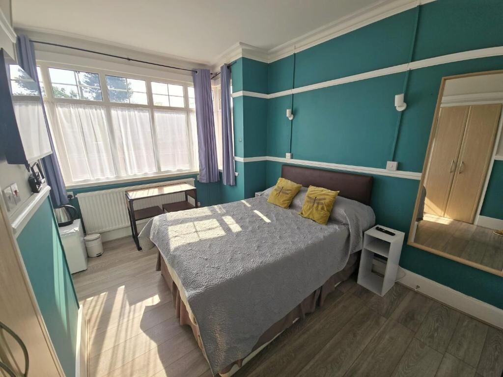 Una camera da letto con un letto, una finestra, un termosifone, un armadio e un tavolino.