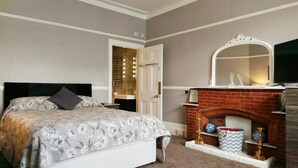 Un dormitorio con cama, chimenea y espejo.