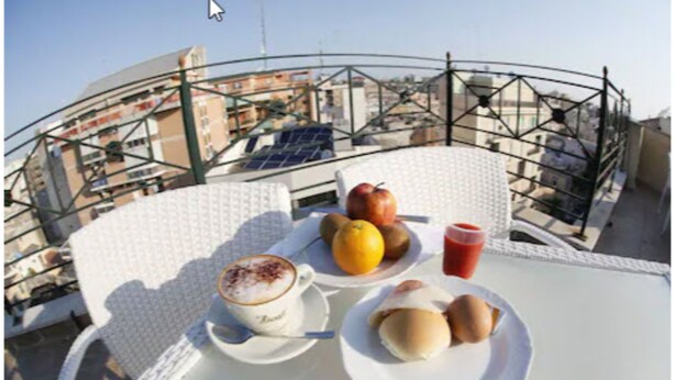 Ein Tisch mit einer Kaffeetasse, Brot auf einem Teller und Obst auf einem Balkon.