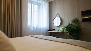 Una habitación de hotel con cama, escritorio, teléfono, espejo y televisión en la pared.