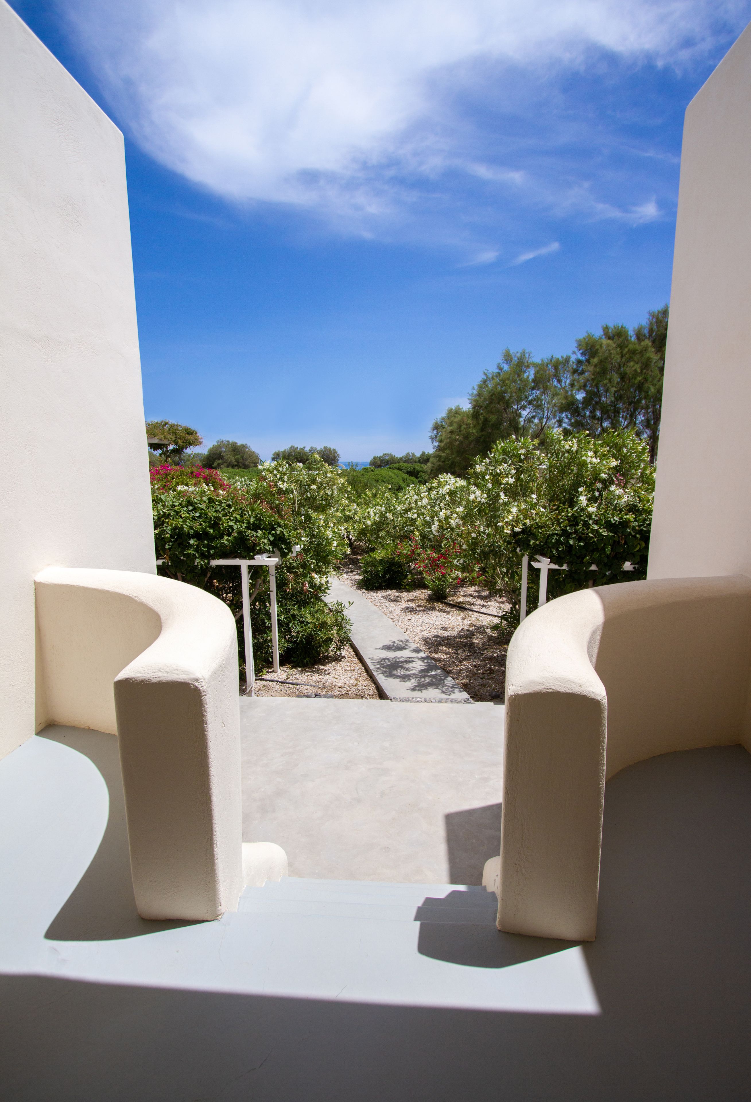 A balcony with a view of a garden and a clear blue sky.