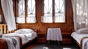 A wooden cabin room with two beds, a small table, and large windows with curtains. - Willa Orla (Zakopane)