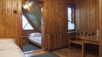 Una habitación tipo cabaña de madera con una cama, una mesita y una ventana.