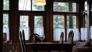 A room with large windows, a wooden table, chairs, and a hanging lamp. - Willa Orla (Zakopane)