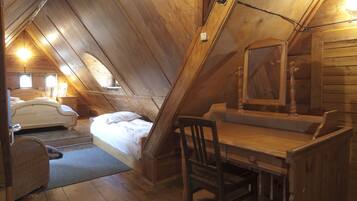 Un dormitorio acogedor en el ático, con techo de madera, cama, escritorio y silla.