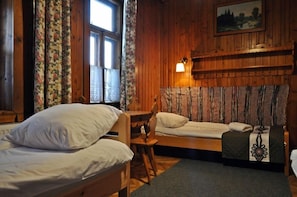 A wooden cabin room with two beds, a chair, a table, and a lamp. - Willa Orla (Zakopane)