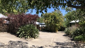 A residential driveway with a house, surrounded by various plants and trees. - Emeraldene Inn & Eco-Lodge (Urraween)