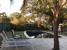Una piscina con borde curvo, rodeada de un patio empedrado.
