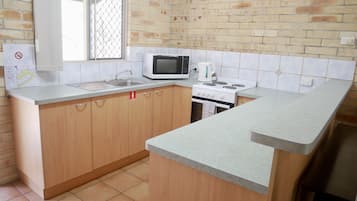 A kitchen with a microwave, stove, sink, and wooden cabinets.