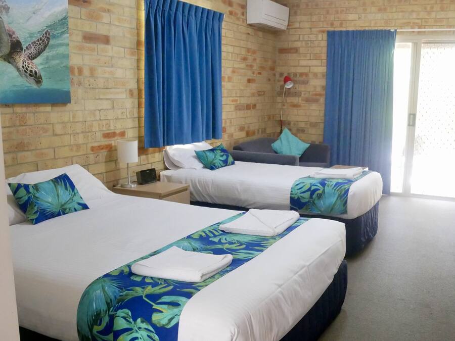 Una habitación de hotel con dos camas, un muro de ladrillo y un cuadro de una tortuga marina.