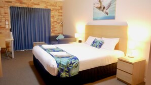 A hotel room with a large bed, two bedside tables, a desk, and a chair. - Emeraldene Inn & Eco-Lodge (Urraween)