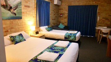 Habitación de hotel con dos camas, un escritorio, una silla y un cuadro de tortuga marina en la pared.