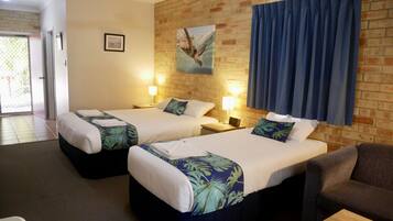 A hotel room with two beds, a brick wall, a painting of a sea turtle, and a view of the outside.