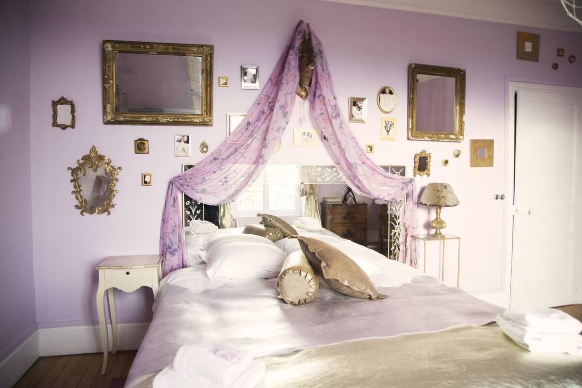 A bedroom with a bed, a nightstand, a lamp, and a mirror on the wall.