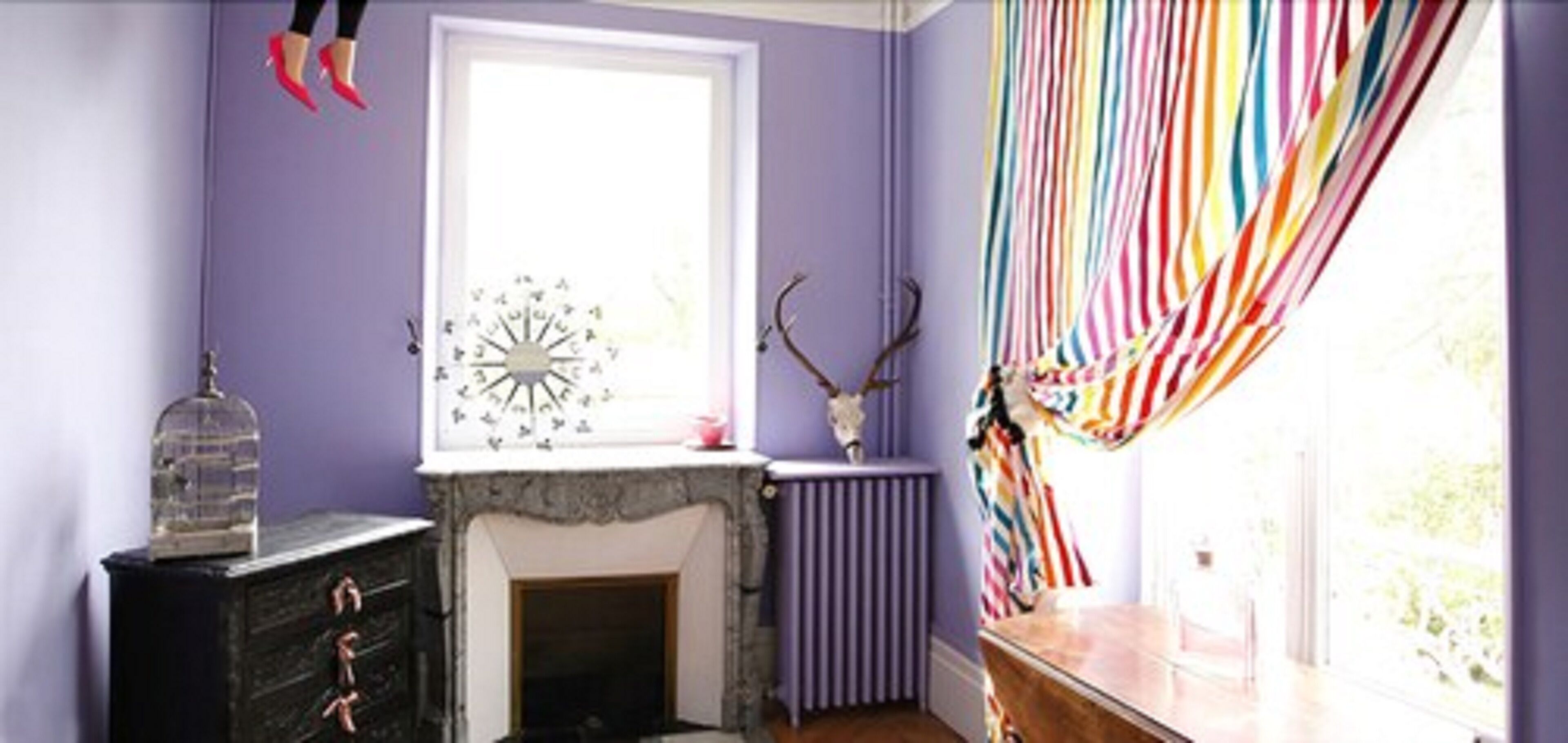 A room with a fireplace, a window with curtains, a radiator, and a decorative clock.