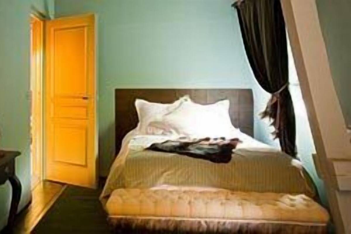 A bedroom with a bed, a desk, and a chair.