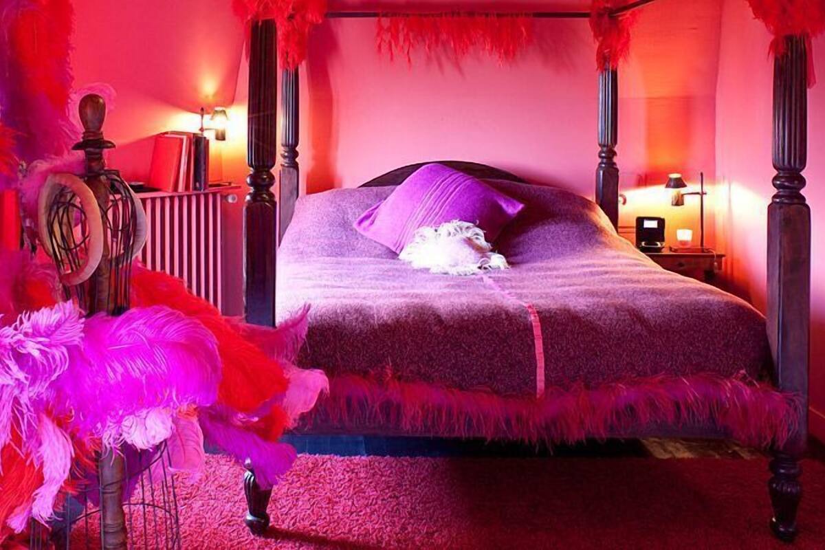 A four-poster bed with a purple bedspread and a single white pillow.