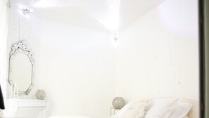 Un dormitorio con cama, mesita de noche y espejo en la pared.