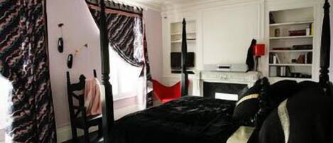 A bedroom with a four-poster bed, a desk with a computer, and a bookshelf.