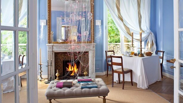 Una habitación con chimenea, una mesa de comedor con sillas y vistas al exterior con vegetación.