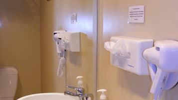 A bathroom with two sinks, a mirror, a hairdryer, and a sign above the mirror.