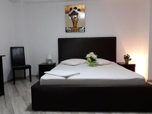 Une chambre à coucher moderne avec un grand lit, une chaise, une table de chevet et une œuvre d’art accrochée au mur.