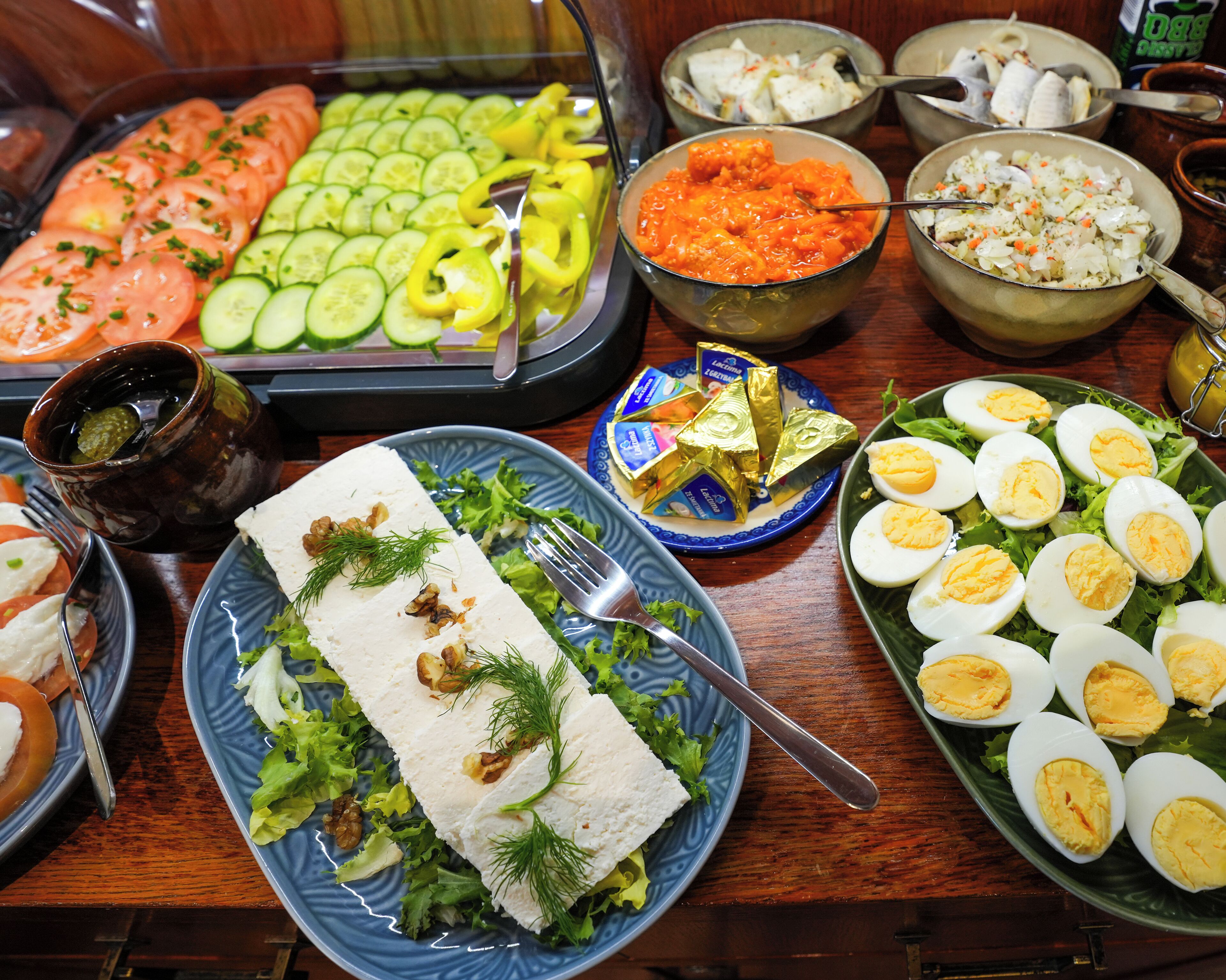 En buffé med olika rätter, inklusive skivad gurka, tomater, morötter och ägg.