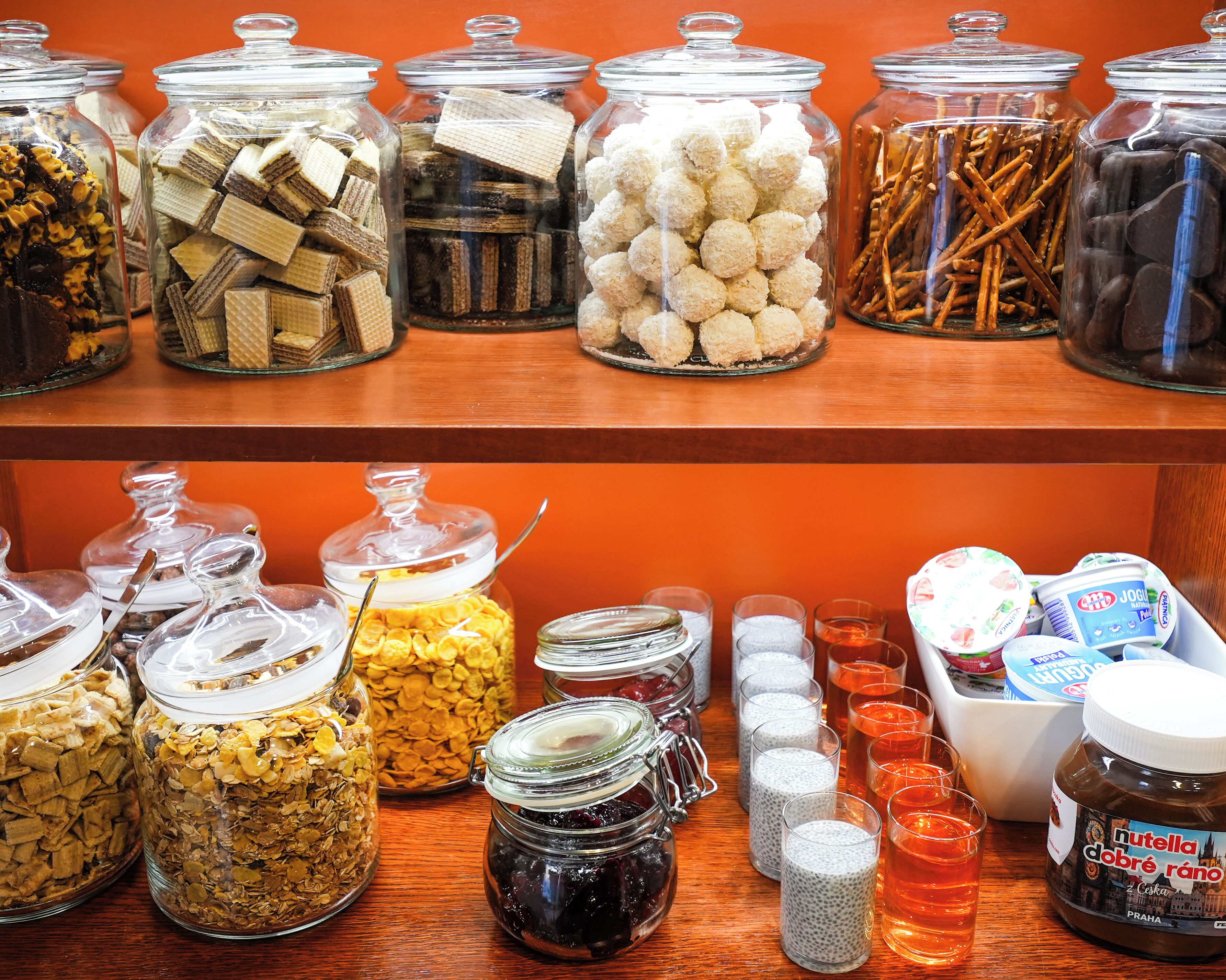 A variety of food items in glass jars on shelves, including cookies, pretzels, and other snacks.