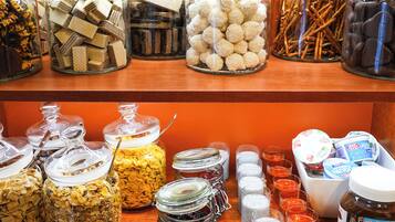 A variety of food items in glass jars on shelves, including cookies, pretzels, and other snacks.