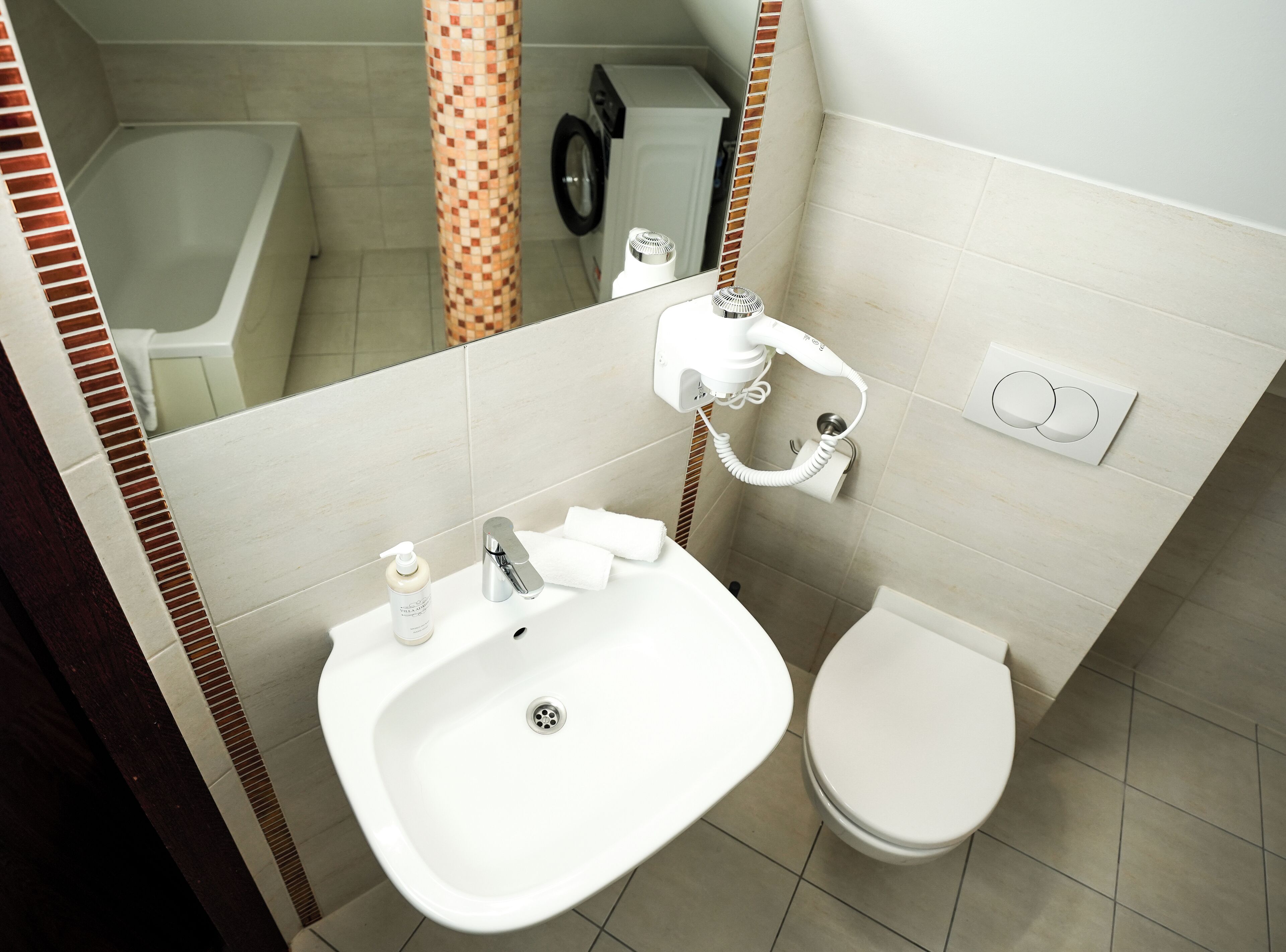 A bathroom with a sink, toilet, and a mirror.
