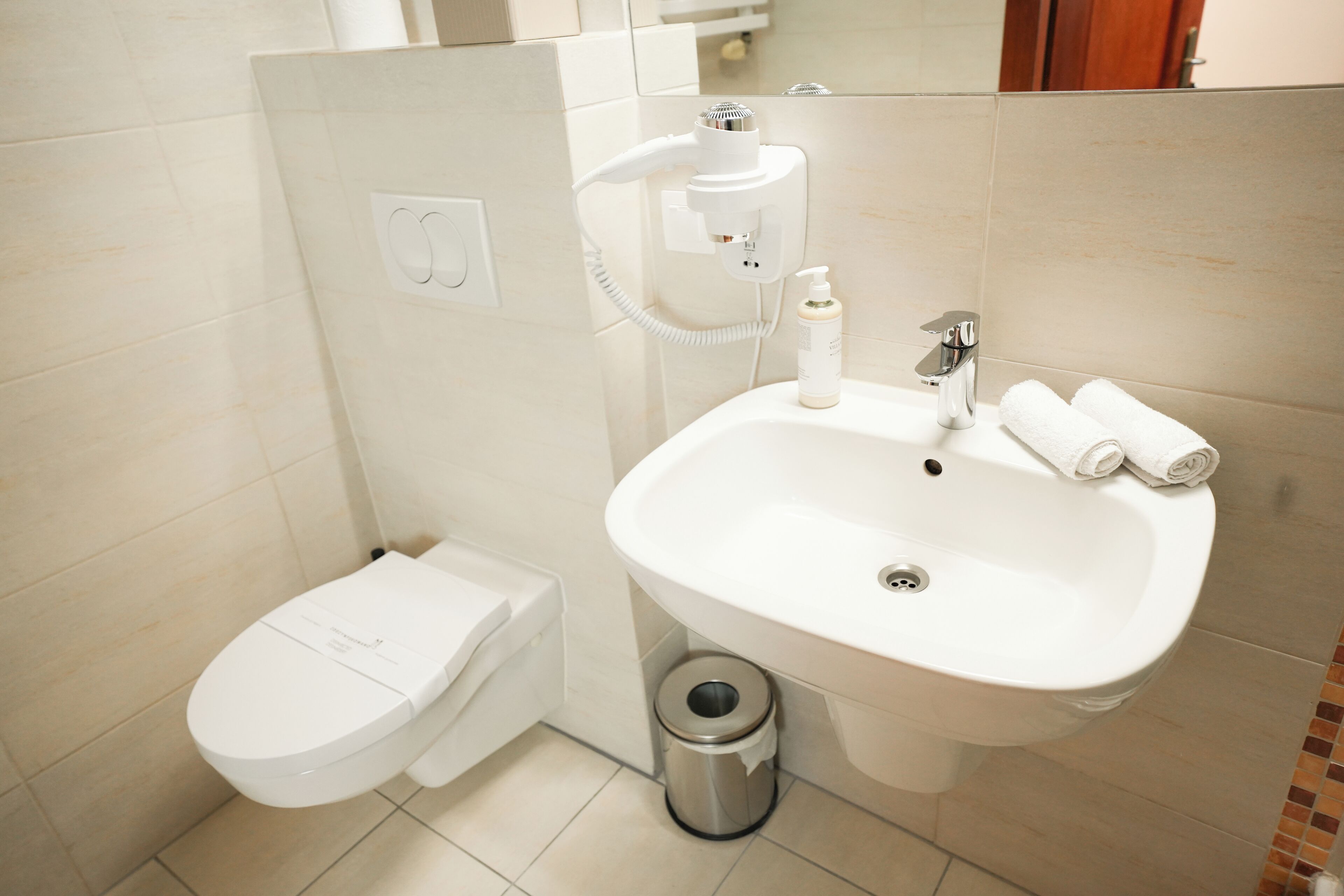 Een moderne badkamer met toilet, wastafel en handdroger.