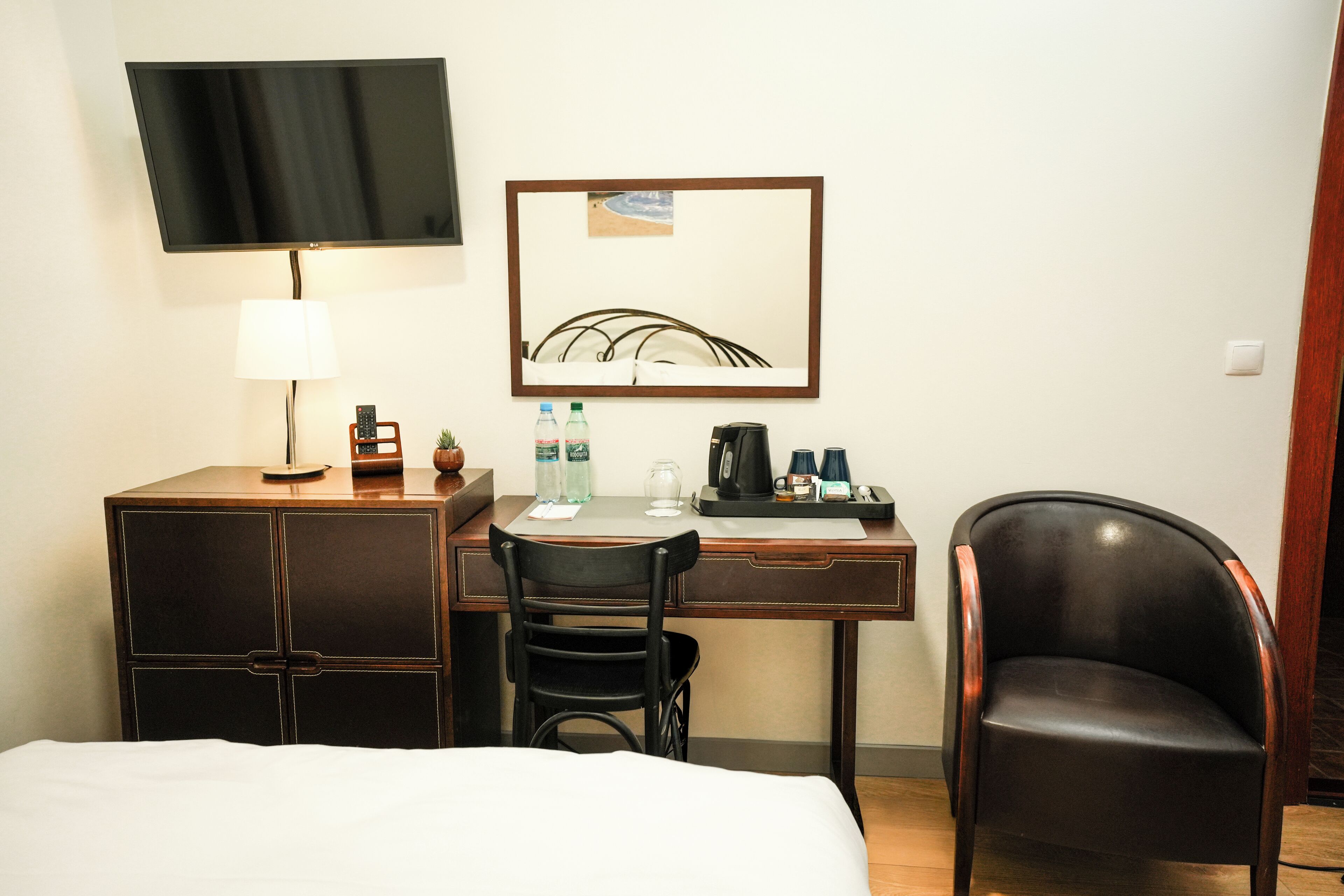 Une chambre d’hôtel avec un lit, un bureau doté d’une lampe, une chaise, un téléviseur et un tableau encadré au mur.