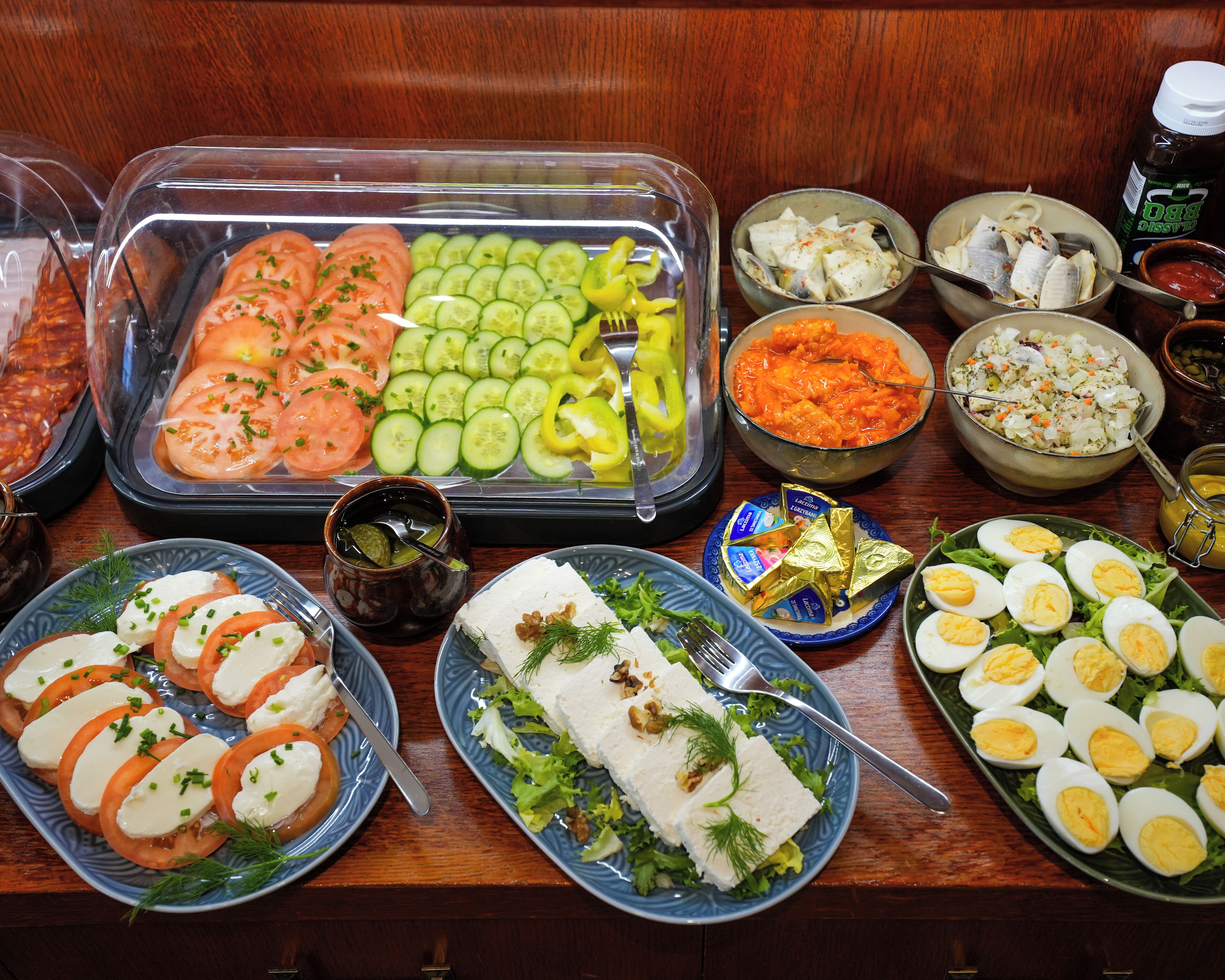 Een buffet met diverse etenswaren, zoals plakjes tomaten, komkommers, paprika en verschillende salades.