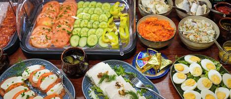 A buffet with various food items including sliced tomatoes, cucumbers, bell peppers, and a variety of salads.