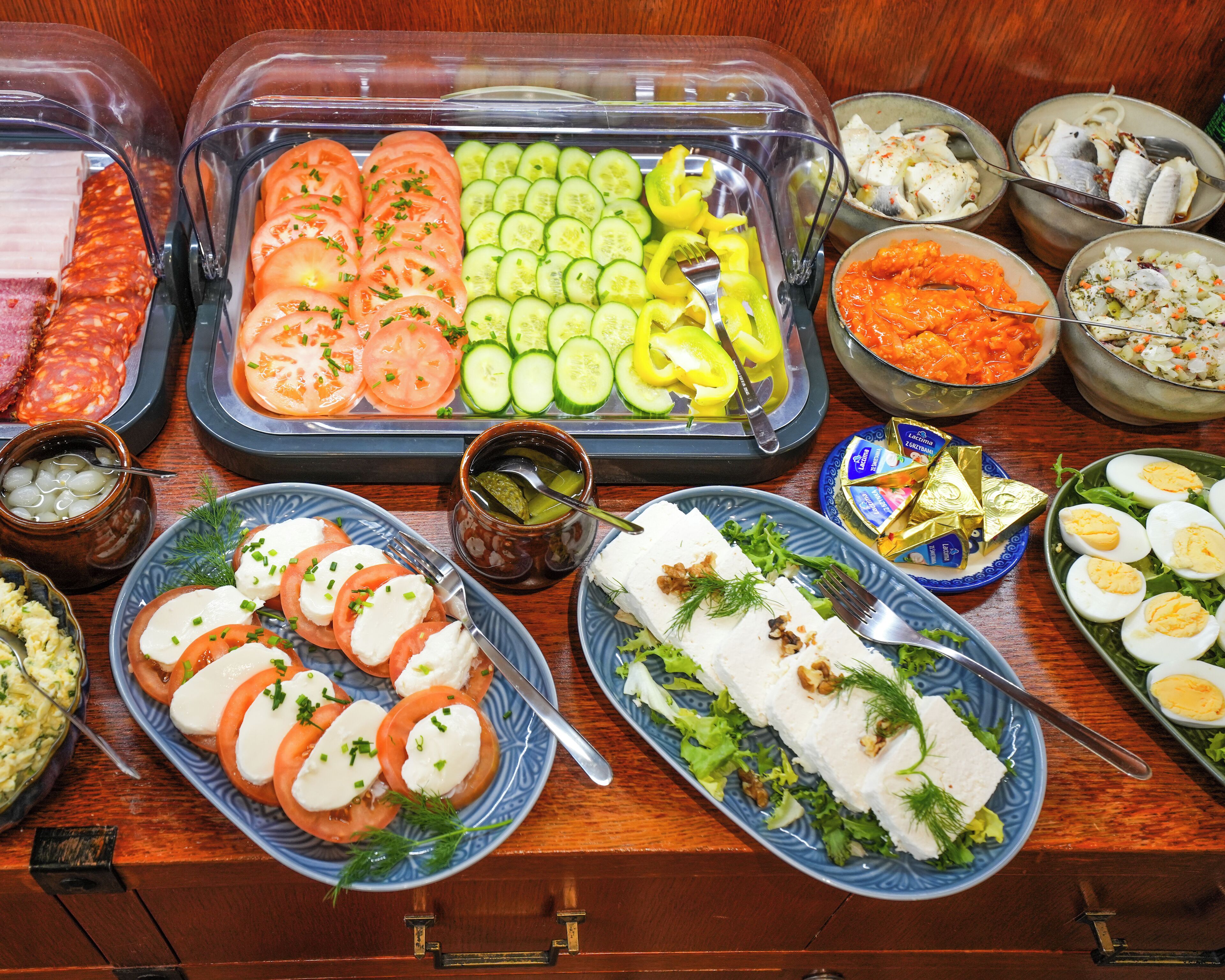 A buffet with various food items including sliced tomatoes, cucumbers, and cheese.