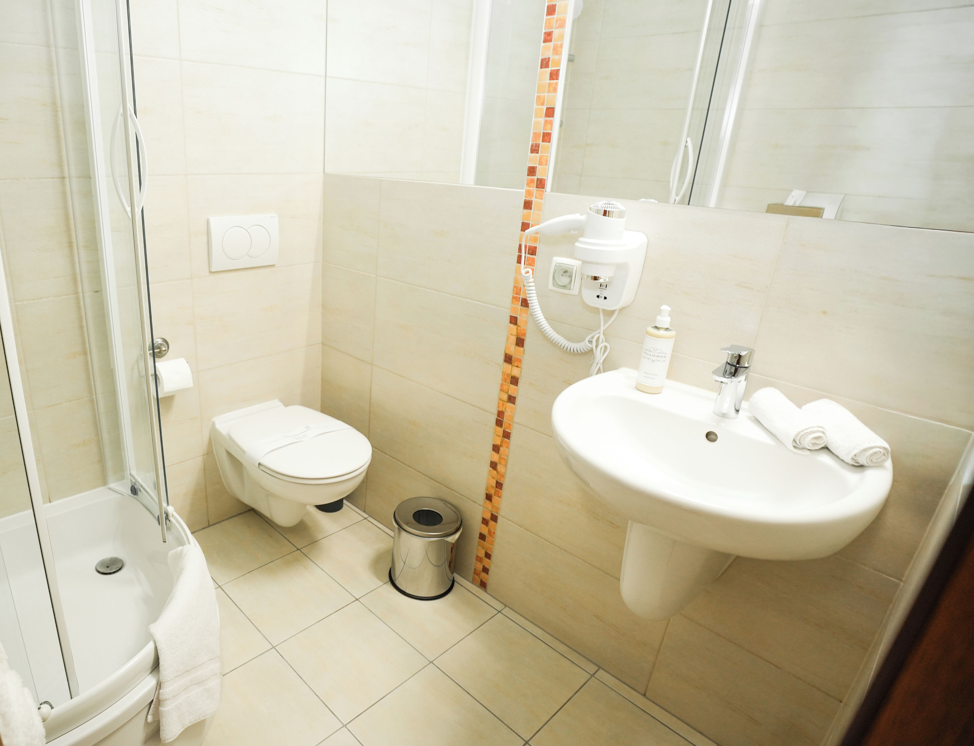 A small bathroom with a toilet, sink, and shower.