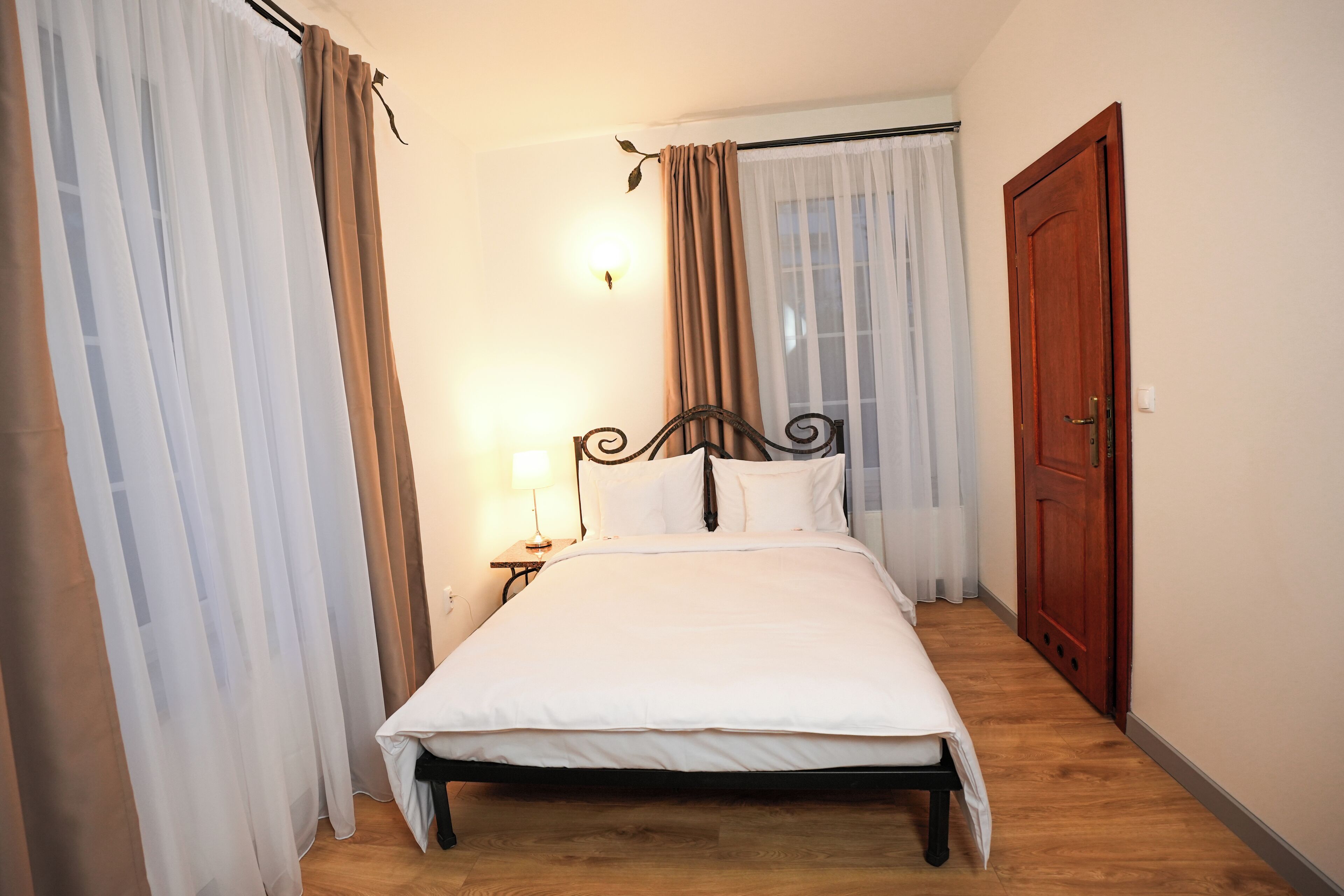 A single bed with a wooden frame, a bedside table with a lamp, and a wooden door.