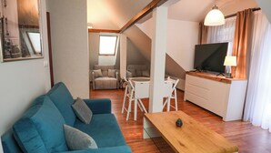 A modern living room with a blue sofa, a wooden coffee table, and a dining area with white chairs. - Villa Admiral (Gdynia)