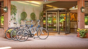 A hotel entrance with a revolving door, bicycles parked outside, and potted plants. - Park Hotel Principe (Collina d'Oro)