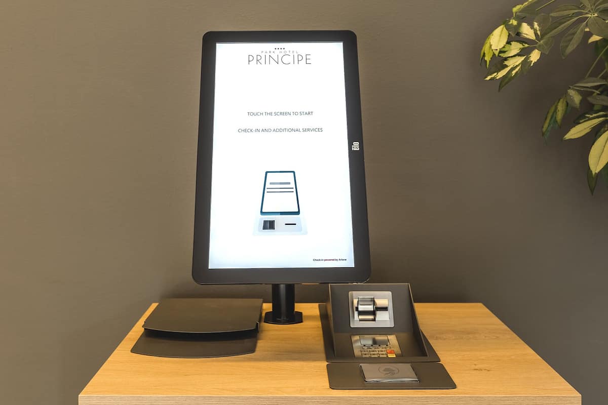 A digital kiosk with a screen displaying a hotel name and instructions for check-in.
