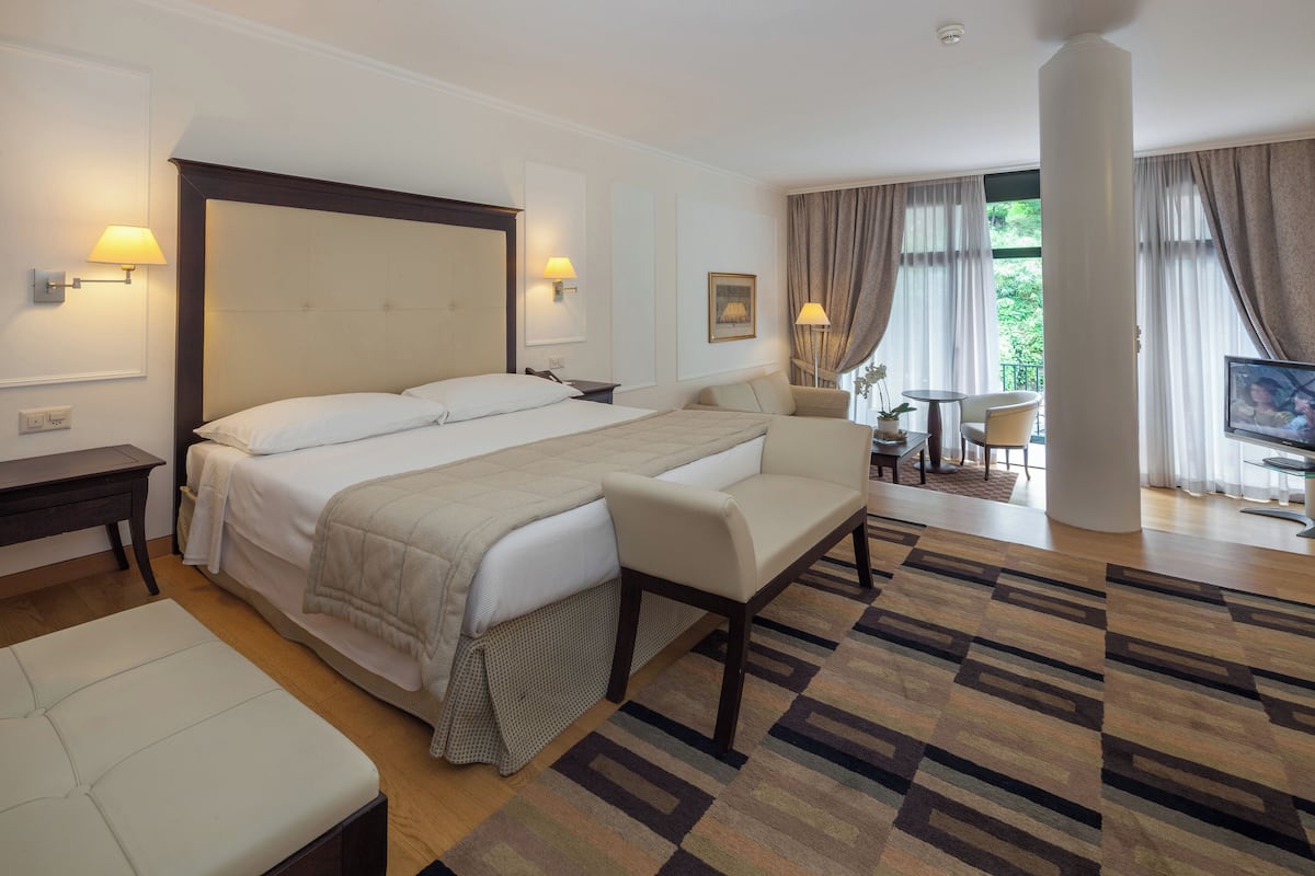 A hotel room with a large bed, a sofa, a desk, and a TV.