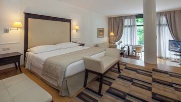 A hotel room with a large bed, a sofa, a desk, and a TV.