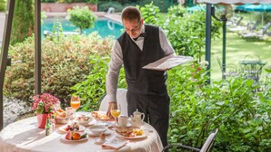 A waiter serving breakfast at an outdoor table with a pool in the background. - Park Hotel Principe (Collina d'Oro)
