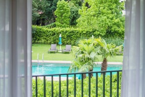 A pool area with a view of a well-maintained lawn, a palm tree, and lounge chairs. - Park Hotel Principe (Collina d'Oro)
