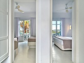 Habitación de hotel con balcón, cama, zona de estar y ventilador de techo.