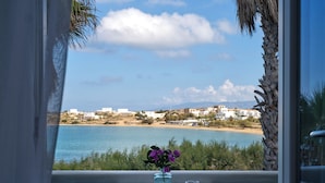 A balcony with a table, chairs, and a vase with purple flowers. - Kalypso Hotel (Paros)